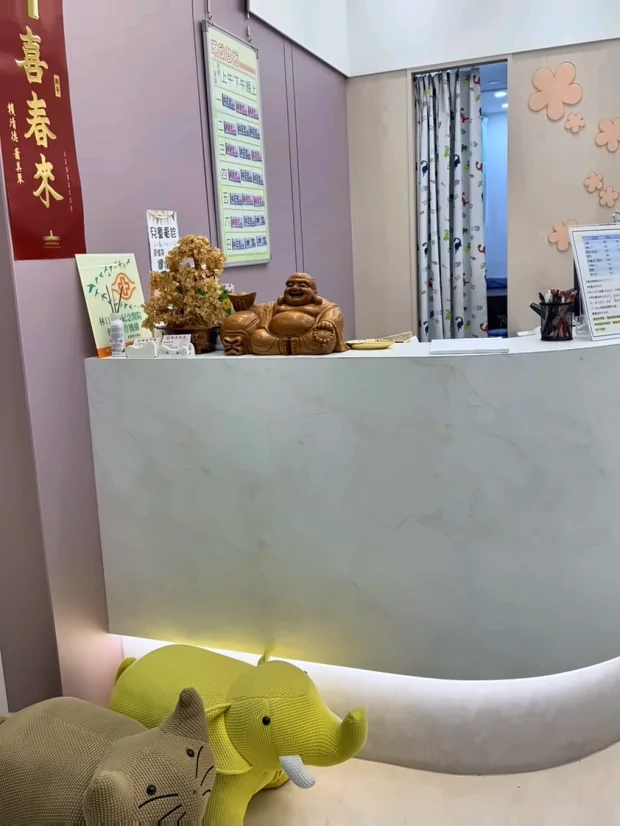 掛號櫃台正面，檯面為白色大理石紋，櫃台前擺著兩隻針織大象與犀牛玩偶